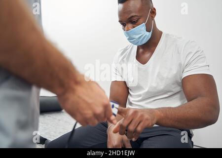 Arzt zur Messung der Sauerstoffsättigung im Blut junger Männer Stockfoto