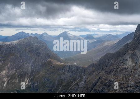 Blick von der Spitze der Trollveggen, oder Troll Wall, in Norwegen. Berühmter Aussichtspunkt in den norwegischen Bergen. Dramatische Bergkette an einem kalten und bewölkten Tag Stockfoto