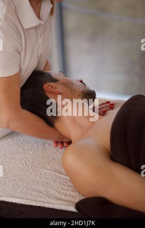 Vertikale, ausgeschnittene Aufnahme eines Mannes, der im Spa-Salon eine professionelle Nacken- und Schultermassage genießt Stockfoto