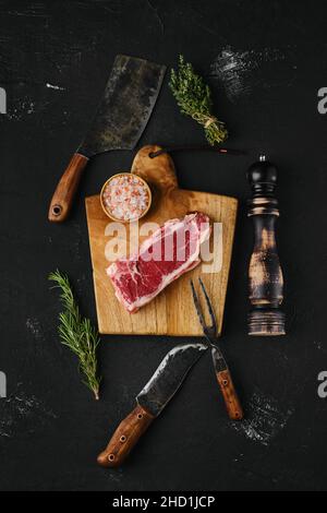 Ansicht von oben von rohem Streifensteak ohne Knochen auf dunklem Hintergrund Stockfoto