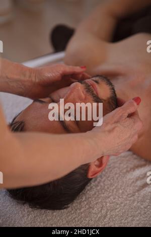 Vertikale Nahaufnahme eines reifen Mannes bei einer professionellen Gesichtsmassage im Spa-Salon Stockfoto