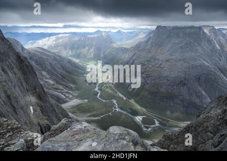 Blick von der Spitze der Trollveggen, oder Troll Wall, in Norwegen. Berühmter Aussichtspunkt in den norwegischen Bergen. Dramatische Bergkette an einem kalten und bewölkten Tag Stockfoto