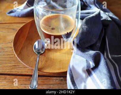 Transparenter doppelwandiger Glaskrug mit Espresso-Kaffee auf rustikalem Holzhintergrund Stockfoto