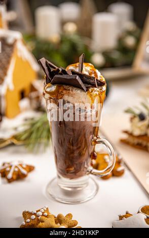 Heiße Schokolade mit Schlagsahne, Schokoriegel und Karamellsauce in hohem Glas Stockfoto