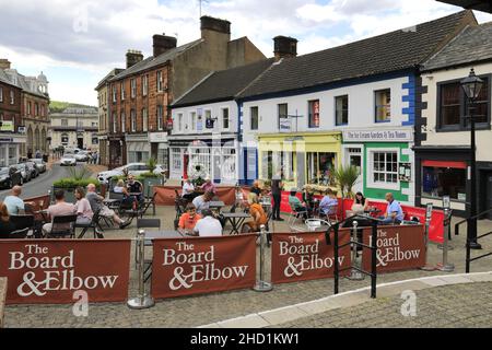 Personen außerhalb des Verwaltungsrats und des Elbow Pub, Penrith Town, Cumbria, England, Großbritannien Stockfoto