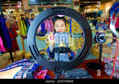 QIANDONGNAN, CHINA - 10. DEZEMBER 2021 - He Chunzhi, eine weibliche Anchor eines ethnischen Bekleidungsunternehmens, verkauft ethnische Stickprodukte über Online-li Stockfoto