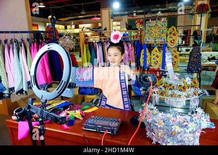 QIANDONGNAN, CHINA - 10. DEZEMBER 2021 - He Chunzhi, eine weibliche Anchor eines ethnischen Bekleidungsunternehmens, verkauft ethnische Stickprodukte über Online-li Stockfoto