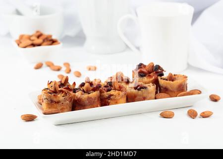 Kleine Kuchen mit Mandeln, Rosinen und Honig auf einem weißen Tisch. Stockfoto