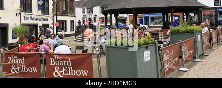 Personen außerhalb des Verwaltungsrats und des Elbow Pub, Penrith Town, Cumbria, England, Großbritannien Stockfoto