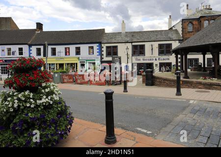 Personen außerhalb des Verwaltungsrats und des Elbow Pub, Penrith Town, Cumbria, England, Großbritannien Stockfoto