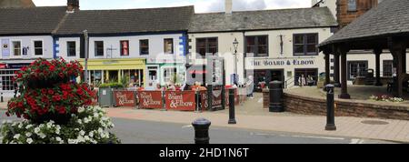 Personen außerhalb des Verwaltungsrats und des Elbow Pub, Penrith Town, Cumbria, England, Großbritannien Stockfoto