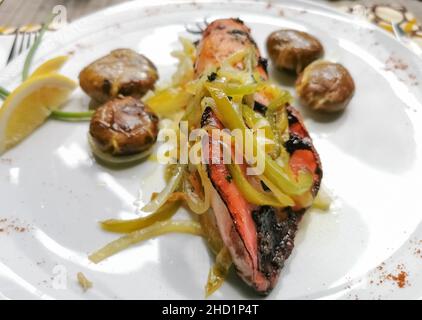 Gesundes gegrilltes Tintenfischgericht gefüllt mit Gemüse, grünen Paprika und Zwiebeln, gebackenen Kartoffeln und Zitronenscheibe... Stockfoto