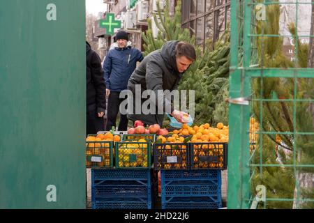 Krasnodar, Russland - 25 2021. Dezember: Der Mensch wählt auf einem Straßenmarkt Mandarinen aus und steckt sie in eine Plastiktüte Stockfoto