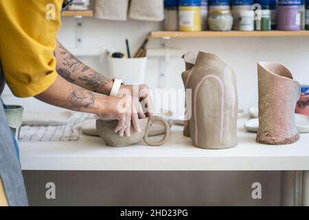 Weibliche Keramikerin, die im Studio Becher macht, Frau, die während des Töpferhandwerks mit Ton arbeitet Stockfoto