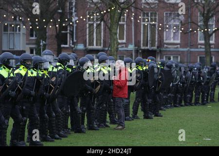 Amsterdam, Niederlande. 02nd Januar 2022. Während einer illegalen Demonstration der rechtsextremen Anti-Vaxxer gegen die Beschränkungen des Coronavirus am Museumplein inmitten der Coronavirus-Pandemie am 2. Januar 2022 in Amsterdam, Niederlande, steht ein Protestant vor der niederländischen Anti-Riot-Polizei. Die Bürgermeisterin Femke Halsema klassifizierte den Museumplein als „Sicherheitsrisikogebiet“, was Polizeibeamten das Recht gab, jeden in diesem Gebiet zu überprüfen und zu durchsuchen, um illegale Demonstrationen und Vandalismus zu verhindern. (Foto von Paulo Amorim/Sipa USA) Quelle: SIPA USA/Alamy Live News Stockfoto