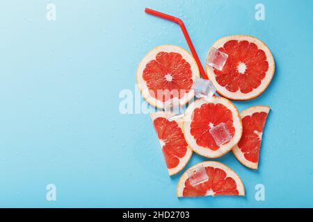 Eine Komposition aus Grapefruitscheiben und Eiswürfeln mit blauem Hintergrund in Form eines erfrischenden Getränks. Draufsicht, freier Platz Stockfoto