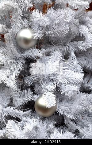 Weiße Weihnachtsdekoration mit Kugeln auf Tannenzweigen. Stockfoto