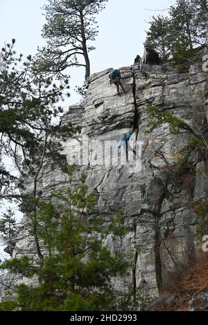 Ein Paar rappelt auf dem Ledge Spring Trail im Pilot Mountain State Park in North Carolina an einer Klippe hinunter. Stockfoto