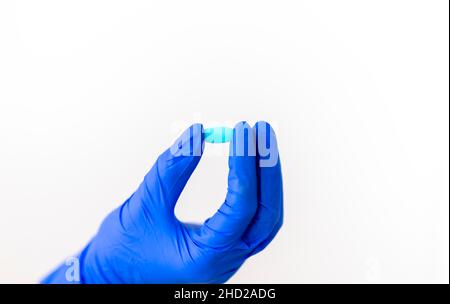Der Arzt hält Medikamente, Pillen, Pillen, eine Hand in blauen Handschuhen. Kapseln auf der Hand eines Forschers mit einem blauen Handschuh. Stockfoto