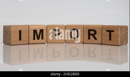 Importieren Sie das Wort, das in Holzwürfeln auf weißem, glänzenden Hintergrund geschrieben wurde Stockfoto