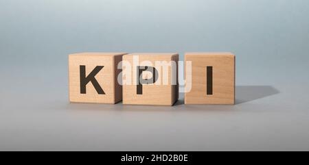 Akronym KPI – Key Performance Indicator. Holzwürfel mit Buchstaben isoliert auf grauem Hintergrund Stockfoto
