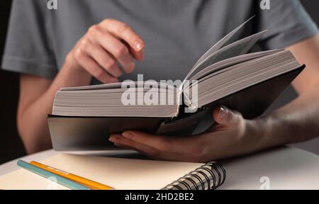 Studentinnen zeigen in der Nähe auf Text in Büchern oder Lehrbüchern, suchen nach Informationen und lesen nachts. Stockfoto