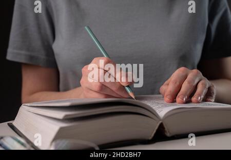 Weibliche Studenten Hände halten Bleistift und Buch lesen, bereiten Sie sich auf die Prüfung am Tisch in der Nacht. Bildungskonzept. Stockfoto