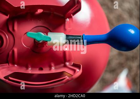 Selektiver Fokus auf den Rand eines aufblasbaren Ballons, der an einem Heliumbehälter befestigt ist. Stockfoto