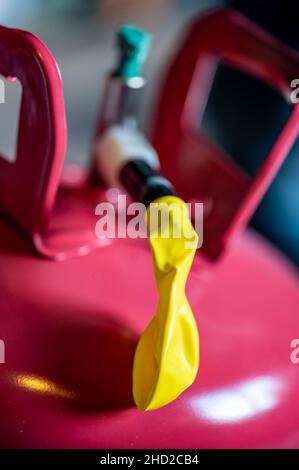 Selektiver Fokus auf den Rand eines aufblasbaren Ballons, der an einem Heliumbehälter befestigt ist. Stockfoto