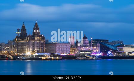 Die drei Grazien (bestehend aus dem Royal Liver Building, dem Cunard Building und dem Port of Liverpool Building) beginnen zu leuchten, wenn die Dunkelheit versinkt Stockfoto