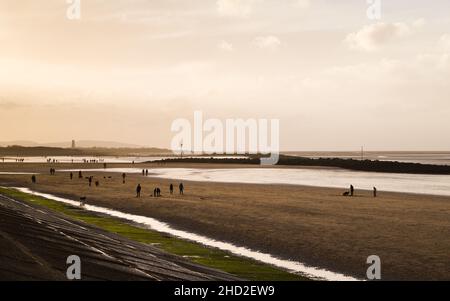 Leaseowe Beach bei Ebbe eingefangen angesichts der späten Nachmittagssonne am 1. Januar 2022, Silhouetten Leaseowe Leuchtturm in der Ferne. Stockfoto