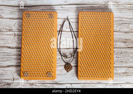 Halskette Mit Om-Symbol. Braune Sadhu Holzbretter mit Nägeln für Yoga und spirituelle Übungen auf dem grauen Hintergrund. Das Konzept der Meditation. Stockfoto