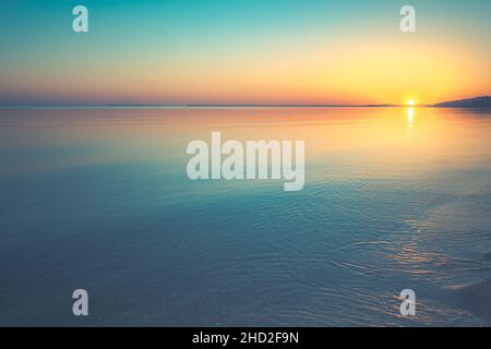 Sonnenuntergang über Wasser und Küste in der Ferne Stockfoto