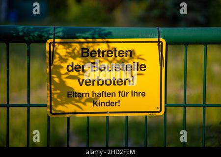 Warnschild an einem Zaun mit deutschem Text übersetzt in Baustelle nicht in englischer Sprache eingeben Stockfoto