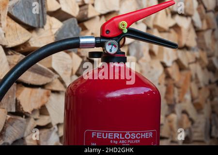 Feuerlöscher: Detail des Manometers, Holzstapel in Backgorund Stockfoto