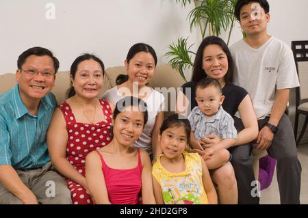 Vietnamesisch-amerikanische Familie zu Hause, gewachsener Sohn mit Frau und Kleinkind Sohn, gewachsene Töchter, Eltern und 8-jährige Tochter Stockfoto