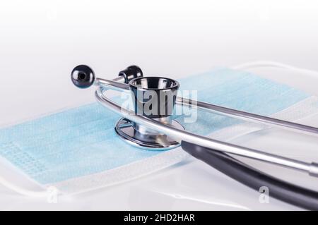 Stethoskop und medizinische Maske auf weißem Hintergrund aus nächster Nähe Stockfoto