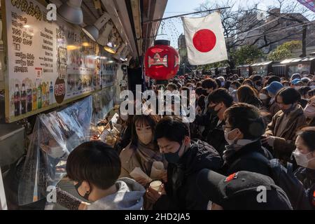 Tokio, Japan. 02nd Januar 2022. Besucher mit Masken kaufen während der Hatsumode im Sens?-Ji Tempel in Asakusa Snacks ein.Hatsumode ist die japanische Tradition, zum ersten Mal im neuen Jahr einen Schrein oder Tempel zu besuchen. Bei dieser Gelegenheit beten die Menschen für Glück und Gesundheit im kommenden Jahr. (Foto: Stanislav Kogiku/SOPA Images/Sipa USA) Quelle: SIPA USA/Alamy Live News Stockfoto