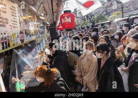 Tokio, Japan. 02nd Januar 2022. Besucher mit Masken kaufen während der Hatsumode im Sens?-Ji Tempel in Asakusa Snacks ein.Hatsumode ist die japanische Tradition, zum ersten Mal im neuen Jahr einen Schrein oder Tempel zu besuchen. Bei dieser Gelegenheit beten die Menschen für Glück und Gesundheit im kommenden Jahr. (Foto: Stanislav Kogiku/SOPA Images/Sipa USA) Quelle: SIPA USA/Alamy Live News Stockfoto