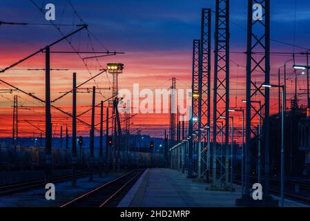 Schöner, flammender Sonnenuntergang über einer Eisenbahn mit vielen Gleisen. Wunderschöner Sonnenuntergang im Bahnhof. Stockfoto