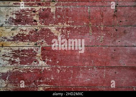 Abgenutzte, rot lackierte Holzplanken-Wand, rustikaler, verzweifelter Hintergrund oder Struktur Stockfoto