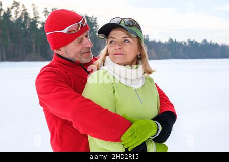 Lächelndes reifes Paar, das im Winter im Park umarmt Stockfoto