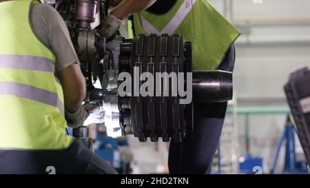 Ruhige Arbeiter, die die Flugmaschine kontrollieren. Flugzeugwartung Mechaniker inspiziert Flugzeugchassis. Motor und Fahrgestell des Passagierflugzeugs unter ihm Stockfoto