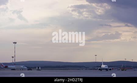 Flughafenmitarbeiter, die Flugzeuge abfertigung. Das Flugzeug parkte am Flughafen und bereitet sich auf den nächsten Flug vor. Nahaufnahme mit Blick auf den weißen, modernen Passagier Stockfoto