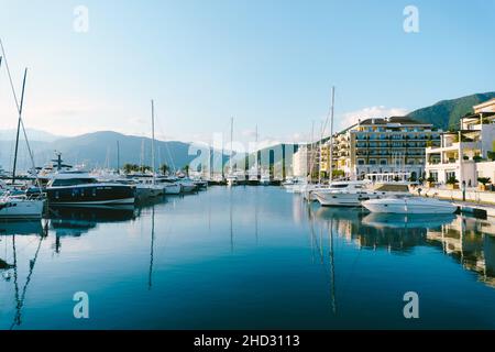 Yachten am Pier vor dem Hintergrund der Küstenhotels in Porto Montenegro Stockfoto