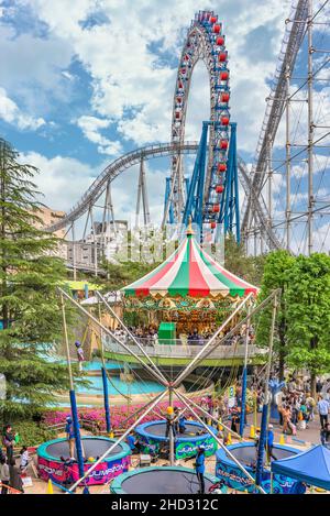 tokio, japan - Mai 03 2019: Familien genießen Trampolin und Karussell in der Laqua Tokyo Dome City Mall, die von der Stahlachterbahn Thunder Dolphin überblickt wird Stockfoto