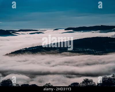 Schöne, strahlende Sonne über Wolken, die Berge bedecken Stockfoto