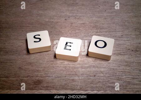 Beschriftierte Kunststofffliesen auf einem Holzbrett mit dem Akronym SEO. Stockfoto