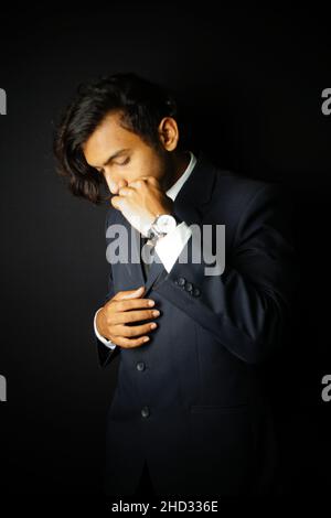 Vertikale Aufnahme eines indischen Mannes in einem edlen Anzug und einer Uhr Stockfoto