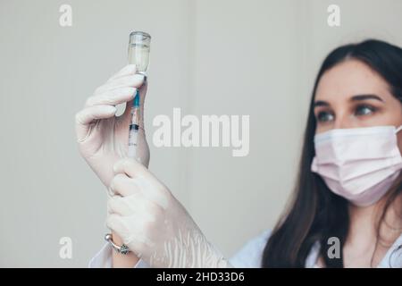 Das Nahaufnahme-Porträt einer Krankenschwester wählt den Impfstoff in eine Spritze. Immunisierung des Corona-Virus. Stockfoto